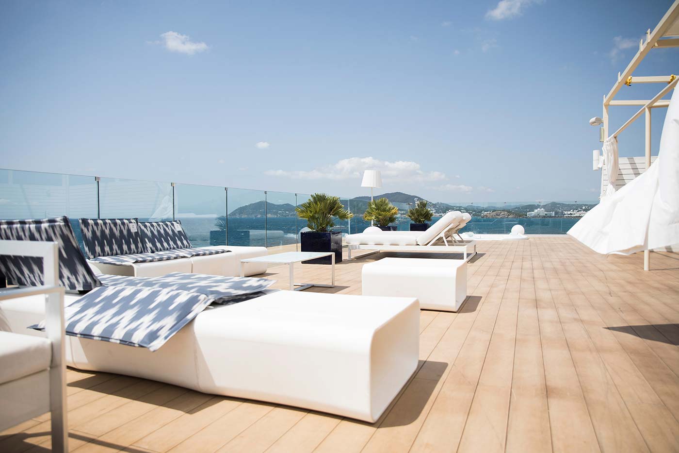 a-roof-top-deck-area-with-white-bright-lounge-chairs-and-spa-overlooking-the-blue-ocean-on-a-sunny_t20_ro7Ydd